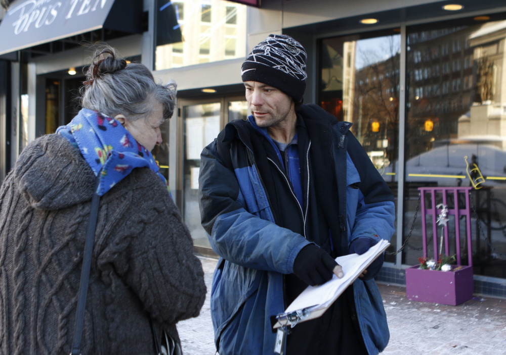 Brandon Scott speaks with Joyce Lorraine on Jan. 21 as he works to collect signatures in Monument Square in Portland on a petition for a casino referendum.