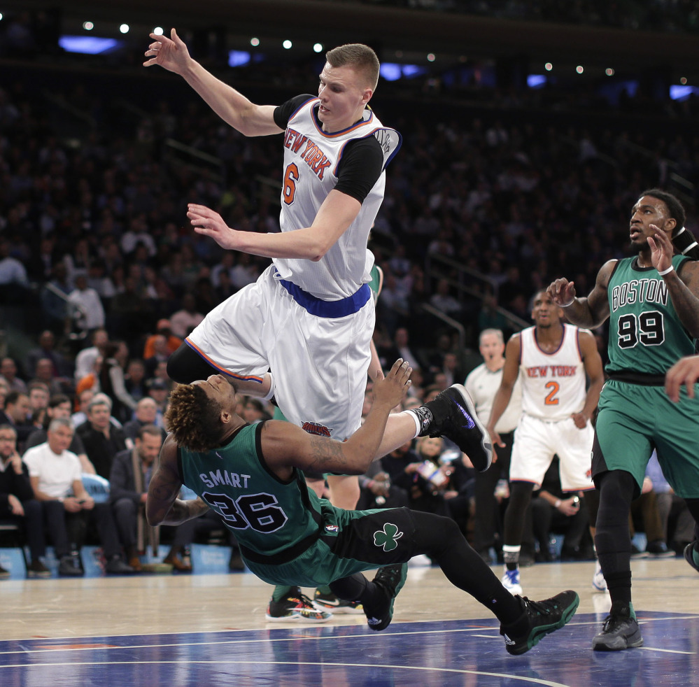 Celtics guard Marcus Smart takes the charge from Knicks forward Kristaps Porzingis in the first quarter. Porzingis was called for an offensive foul on the play.