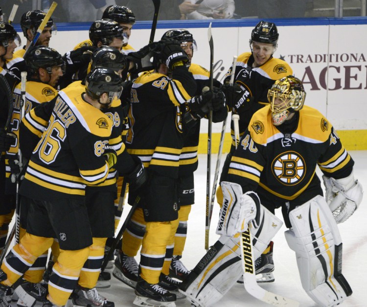 The Bruins surround goaltender Tuukka Rask after he stopped the final shot of the shootout to preserve a 3-2 win Thursday night in Buffalo.