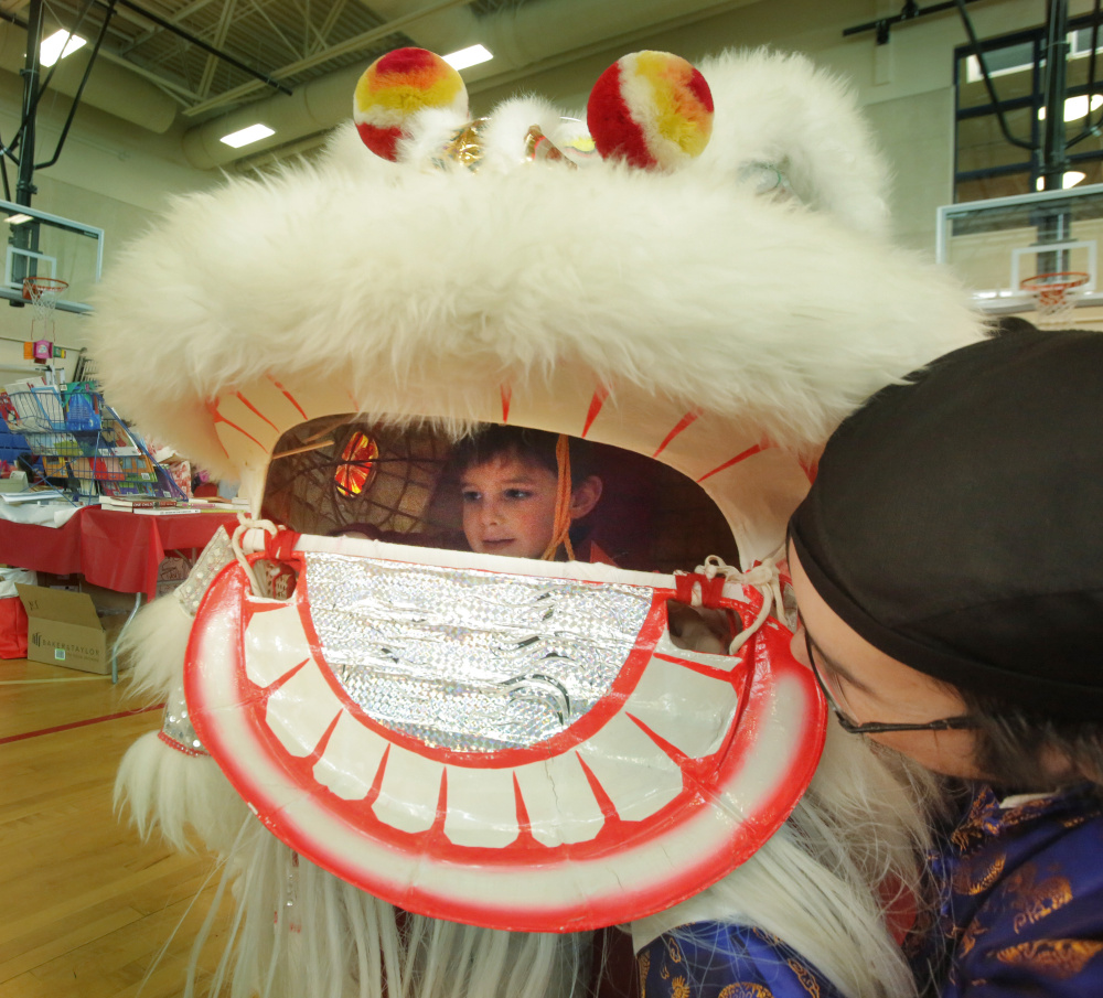Rodger Wong helps Will Lindecamp, 3, try on a lion's head in the gymnasium at Westbrook Middle School during a Chinese New Year celebration sponsored by the Chinese and American Friendship Association of Maine and the Confucius Institute of the University of Southern Maine, on Saturday.