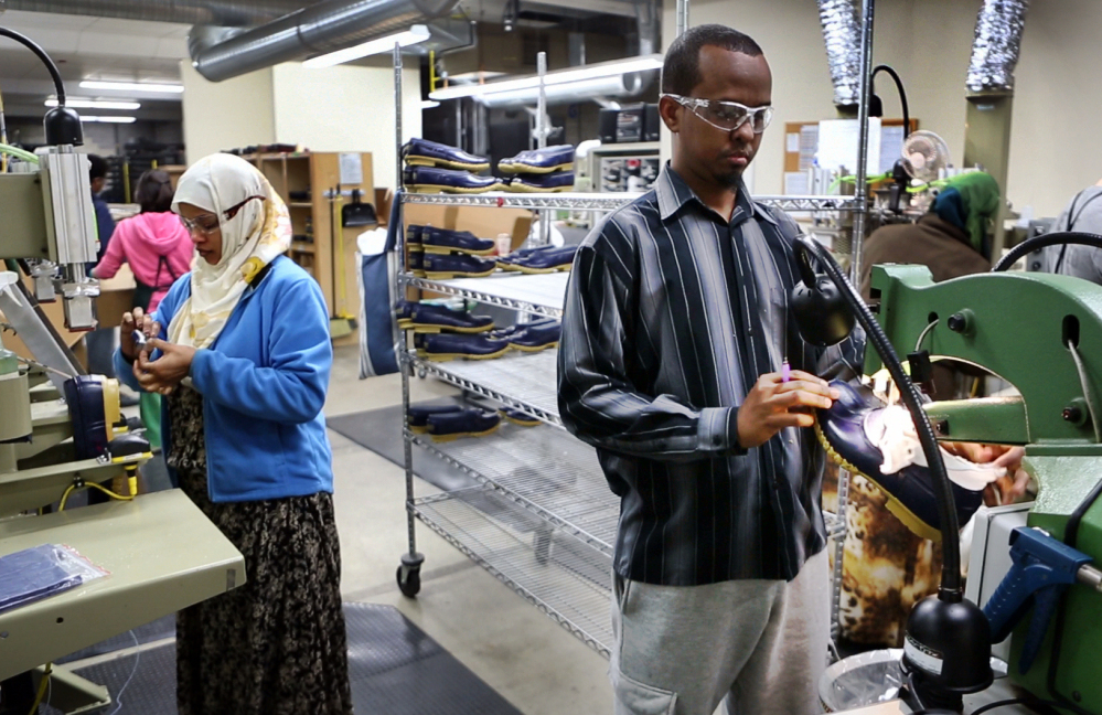In this Tuesday, Jan. 26, 2016 photo, Abdi Said, right, trims the rubber bottoms of Bean Boots at an L.L. Bean factory in Lewiston, Maine. Said, a refugee, was originally put in San Jose, California, before he moved cross-country to Lewiston. “We are working hard and we’re going to school and everything - like regular American people. They see that we are not different,” he said.