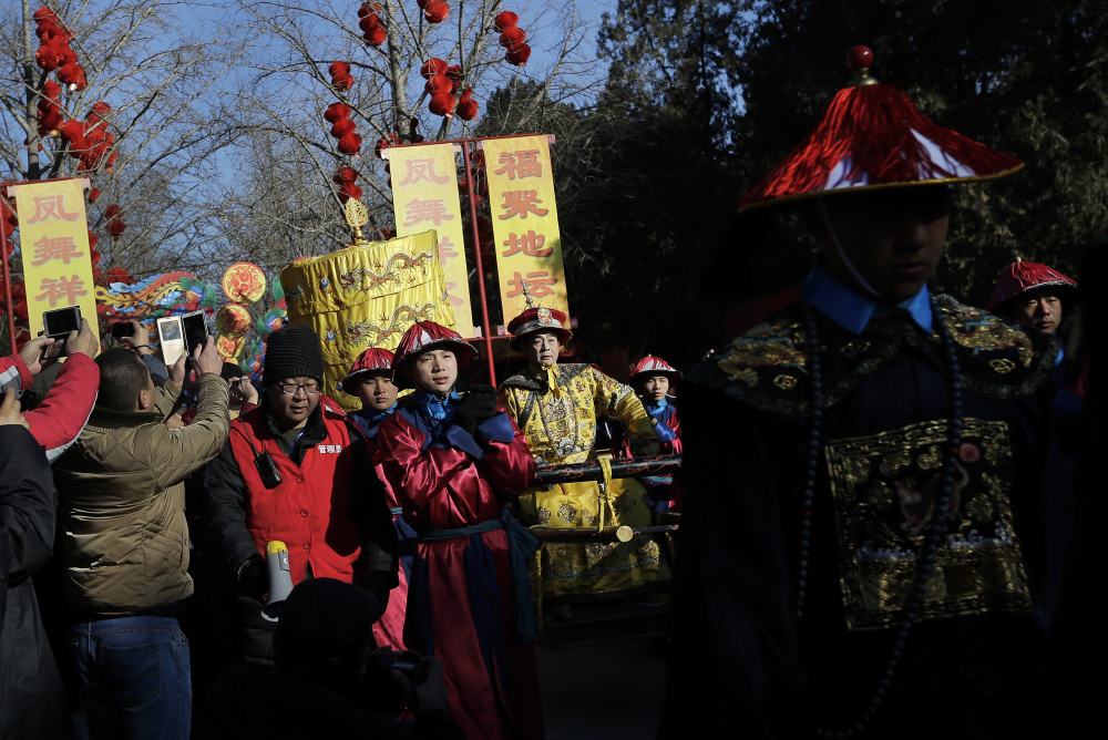 Qi Xue’en, a performer dressed as a Qing Dynasty emperor, seated on a sedan chair, center, is carried during the ancient Qing Dynasty ceremony in which emperors prayed for good harvest and fortune at a temple fair in Ditan Park during the first day of the Chinese Lunar New Year in Beijing, Monday.