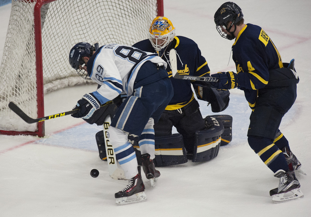 UMaine’s Blaine Bryon gets a look at the goal before being denied by Merrimack’s Collin Delia during second period action on Friday at Orono. Merrimack’s Marc Biega also in on the play. Kevin Bennett Photo