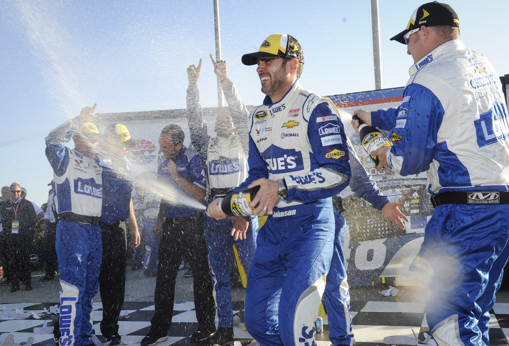 Jimmie Johnson, second from right, celebrates with team members after winning the Sprint Cup Series race Sunday at Atlanta Motor Speedway in Hampton, Georgia. The victory was the 76th of Johnson’s career.