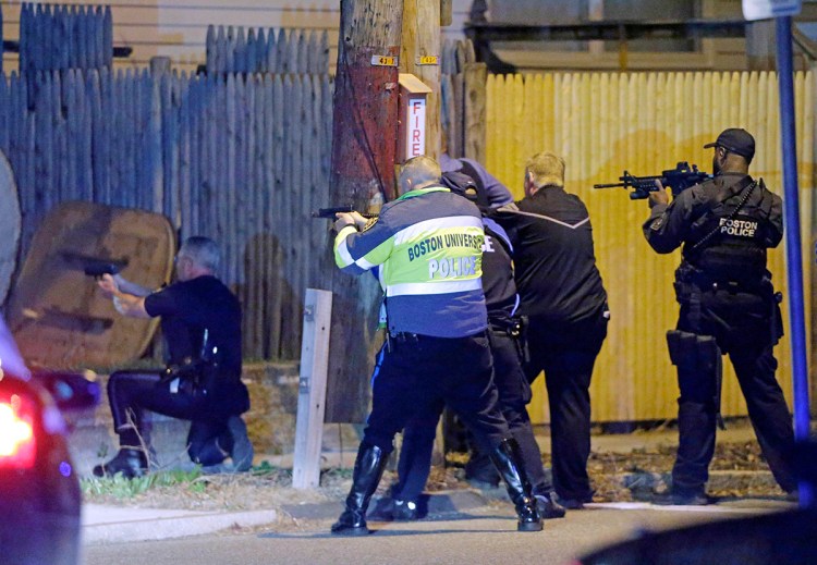 In this April 19, 2013, photo, police aim their weapons in a Watertown, Mass., neighborhood during the hunt for the Boston Marathon bombing suspects. Representatives for "Patriots Day” say they want to recreate the police shootout with the Tsarnaev brothers along the street where it happened. The project would include a week of preparation in April 2016, and a week of nighttime filming in May that could include loud noises like simulated gunfire. The Associated Press