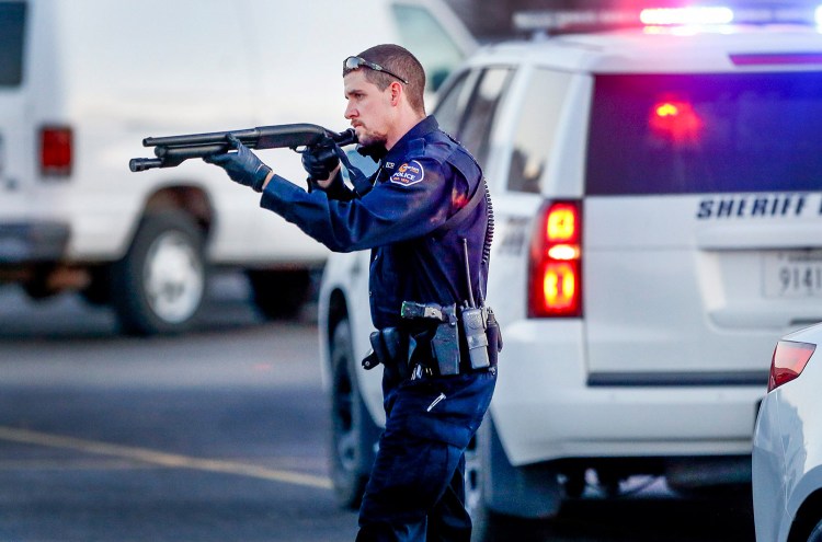 Police go through the parking lot of Excel Industries on Thursday in Hesston, Kan., where a gunman killed four people and injured many more. Fernando Salazar/The Wichita Eagle via AP