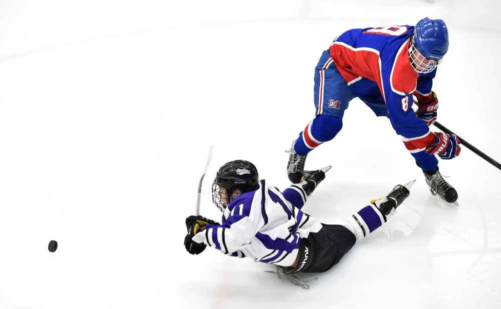 Waterville Senior High School’s Jackson Aldrich (11) gets knocked to the ice by Messalonskee High School’s Dylan Burton (8) in the third period in the Class B North regional final Tuesday at Alfond Arena at the University of Maine at Orono.