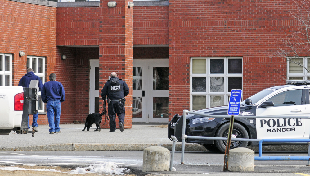 A Bangor police officer and a dog go into Farrington Elementary School during a search following a bomb threat on Friday that closed all Augusta public schools.