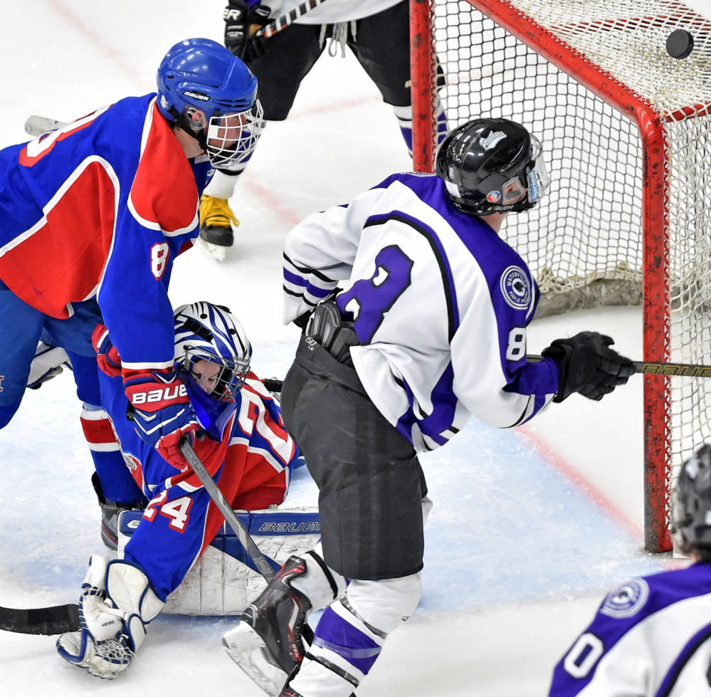 Waterville Senior High School’s Justin Wentworth (8) tries to handle the puck as he tries to score on Messalonskee High School goalie Amber Kochaver in the Class B North regional final Tuesday at Alfond Arena at the University of Maine at Orono.