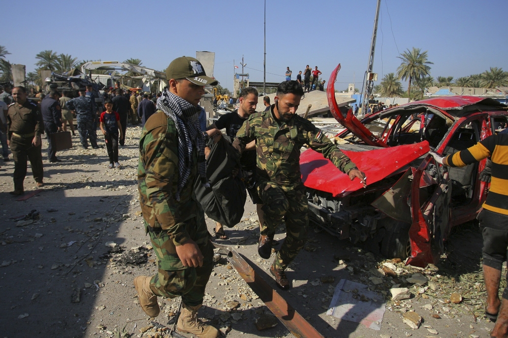 Security forces evacuate a victim’s body after a bombing at a checkpoint crowded with cars and people in Hillah, Iraq.