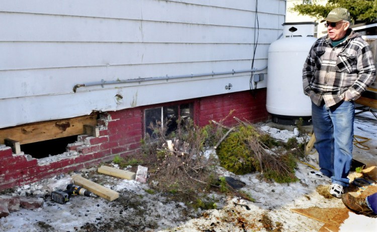 Homeowner Roland Hallee on Sunday looks over the damage to a basement wall on Green Street that was made when a woman crashed her car into the building on Saturday. The woman narrowly missed parked cars and the propane tank, background, before fleeing. She crashed again near Spring Street in Waterville and was arrested.