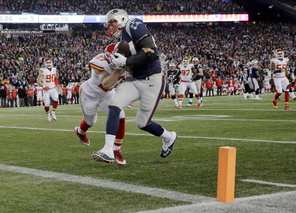 New England Patriots tight end Rob Gronkowski (87) catches a pass for a touchdown ahead of Kansas City Chiefs defensive back Tyvon Branch in the second half of an NFL divisional game Jan. 16 in Foxborough, Massachusetts. The Patriots reportedly picked up an option that will keep the Pro Bowl tight end in New England through 2019.