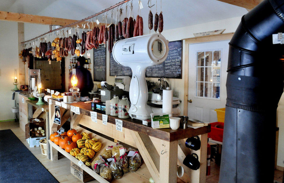 Smoked meat and cheese and fresh vegetables are seen at the Charcuterie shop in Unity, owned by Matt Secich (background), who is Amish. Secich is working with state regulators to comply with state food codes, an issue because of lack of electricity and technology at the shop.