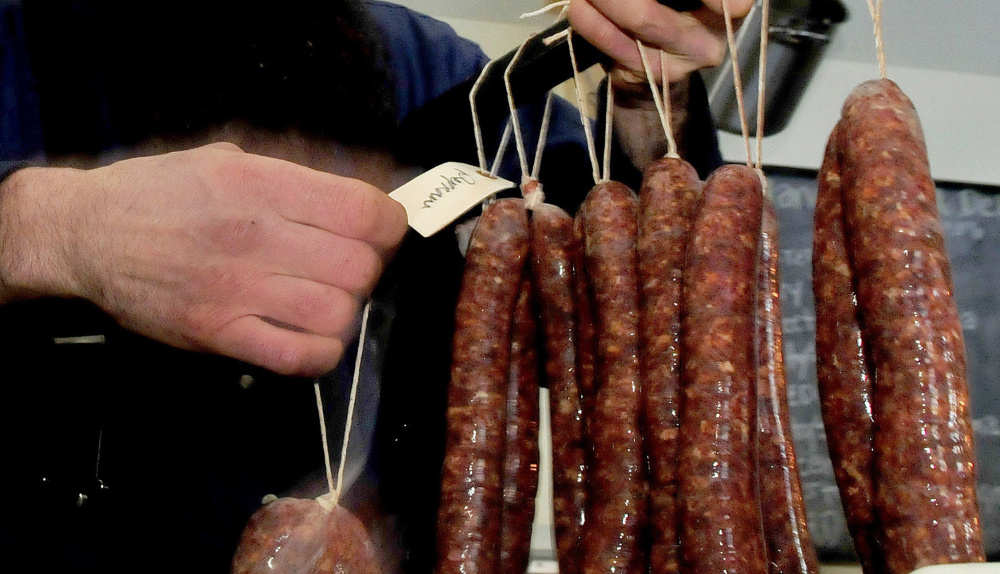 Matt Secich hangs sausages on a bar to dry at his Charcuterie shop in Unity in January. Secich said he may have to close the shop because of the difficulty complying with state regulations given a lack of technology and electricity at the shop.