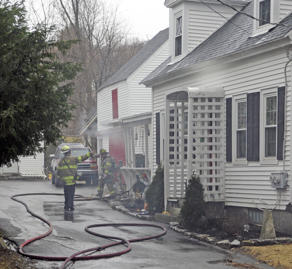 Smoke drifts from the building as firefighters from several area departments work at the scene during a house fire on Thursday at 65 Second St. in Hallowell.