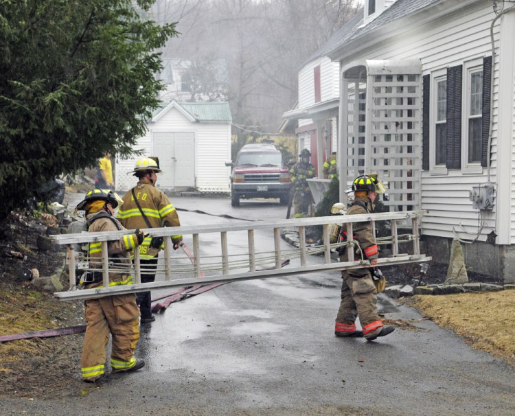 Smoke drifts from the building as firefighters from several departments work at the scene of a house fire on Thursday at 65 Second St. in Hallowell.