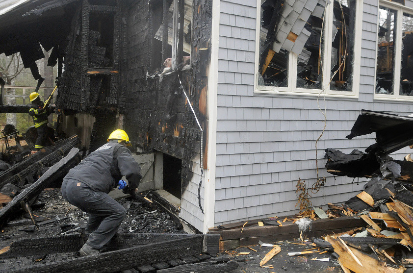 Office of Maine State Fire Marshal investigator Mary MacMaster examines the basement of a home on Collins Mills Road in West Gardiner Thursday that was destroyed by an early morning fire.