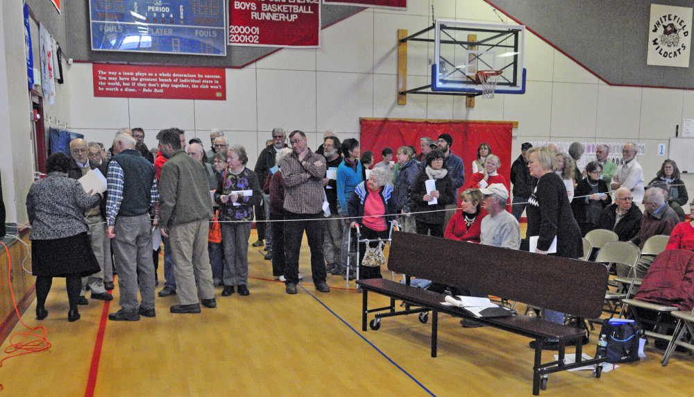 Residents stand on one side of the room and wait to be counted during a division of the house vote on a tax deferral plan during the annual Whitefield Town Meeting on Saturday in the Whitefield Elementary School. The measure was voted down 63-53.