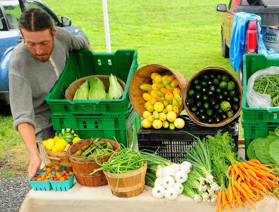 John Strieff sets up the 3 Level Farm booth for the Hallowell Farmers Market in this 2013 file photo taken at Granite City Park in Hallowell. Organizers are proposing to move the market to Vaughan Field Park.