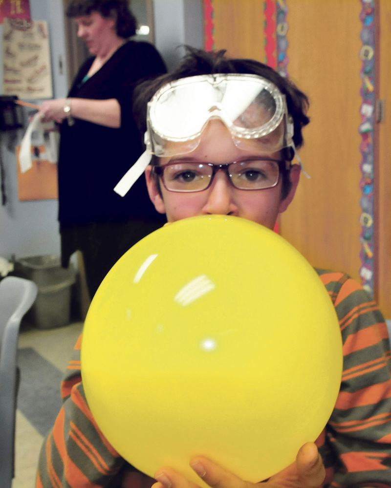Cascade Brook School student Kyeden Thomas blows up a balloon used in a science project with University of Maine in Farmington students teaching the kids on Thursday. Behind Thomas is teacher Lynn Wells.
