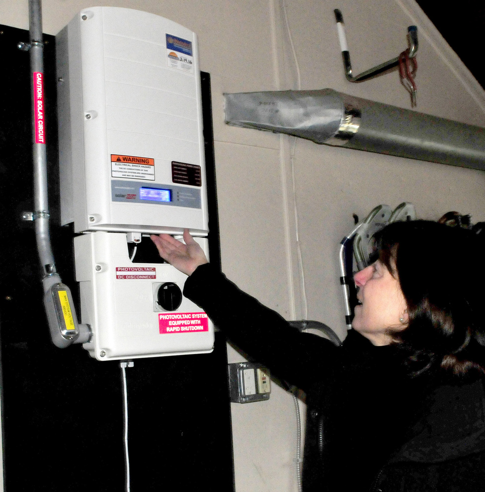 Jan King reads input numbers on an inverter that monitors electricity produced by solar panels on her home in Waterville on Thursday.