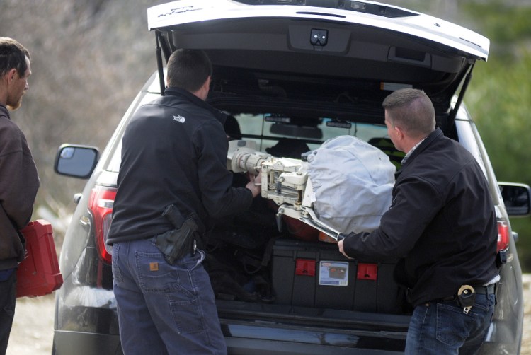 State Police Troop D investigators Adam McNaughton, center, and Elisha Fowlie load a boat motor recovered Thursday from an abandoned house in Chelsea. The troopers were led to the location by Mike Freeman Jr., left, who was arrested on burglary charges.