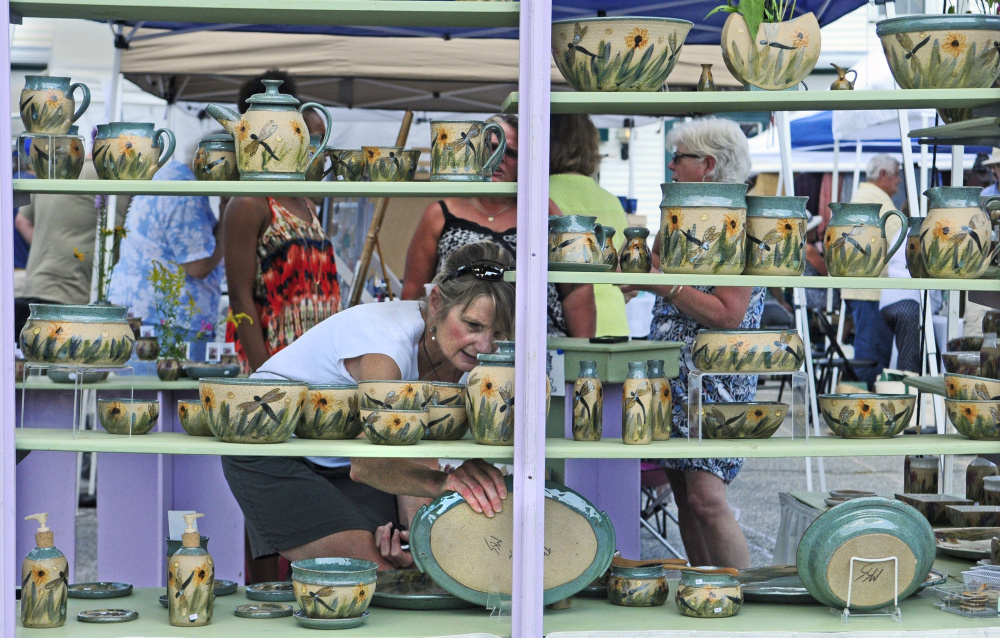 Sue Firlotte of North Monmouth checks out a platter in The Potter’s House booth during the Winthrop Summer Festival last August, when Maine was in the midst of strong third-quarter growth that ranked 16th in the nation.