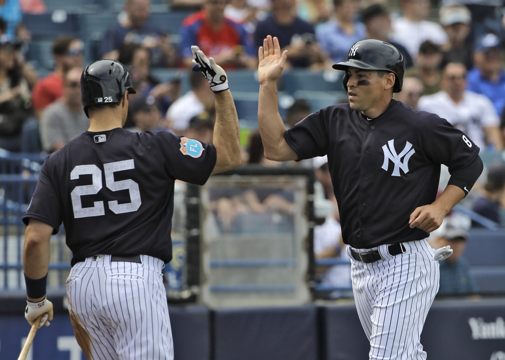 Jacoby Ellsbury, right, of the Yankees high fives on-deck batter Mark Teixeira after scoring on a ground out by Carlos Beltran off Boston Red Sox relief pitcher Robbie Ross Jr. during the fifth inning of a spring training game Saturday. The Yankees went on to win, 6-4.