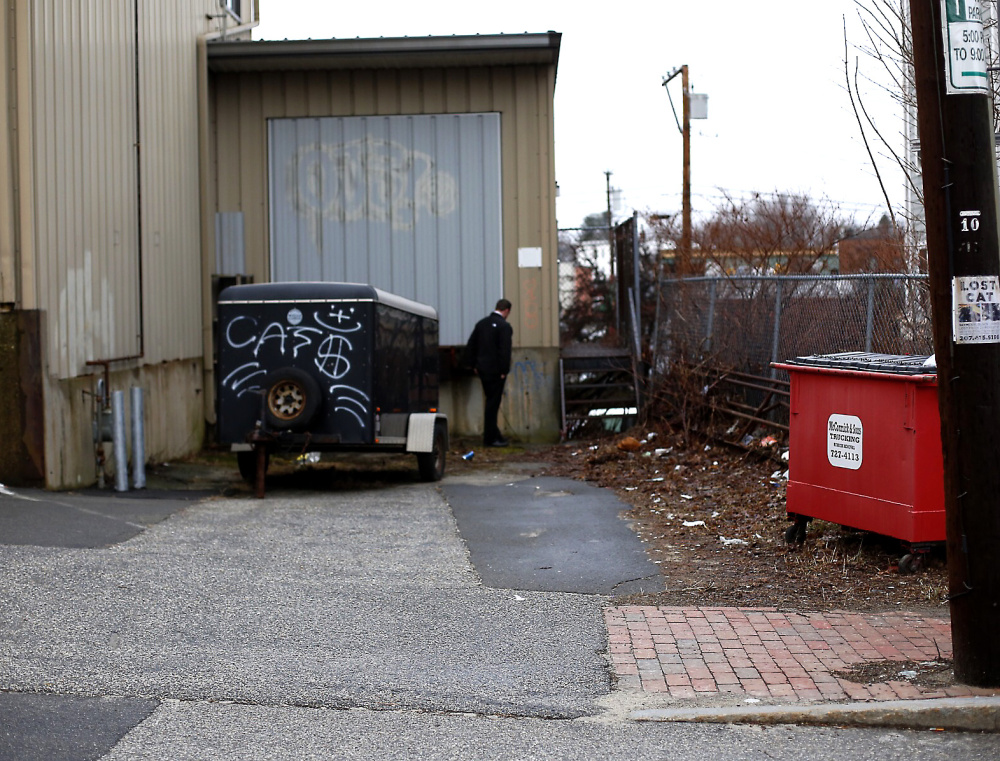 A police detective searches a loading dock area next to the building where police say a shooting happened late Tuesday night.
