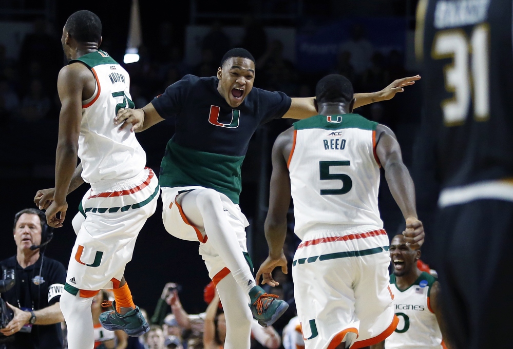 Miami’s Kamari Murphy, left, and Davon Reed (5) celebrate with teammates after defeating Wichita State 65-57 in a second-round game in the NCAA men’s college basketball tournament in Providence, Rhode Sialnd on, Saturday. Miami advances to the Sweet 16.