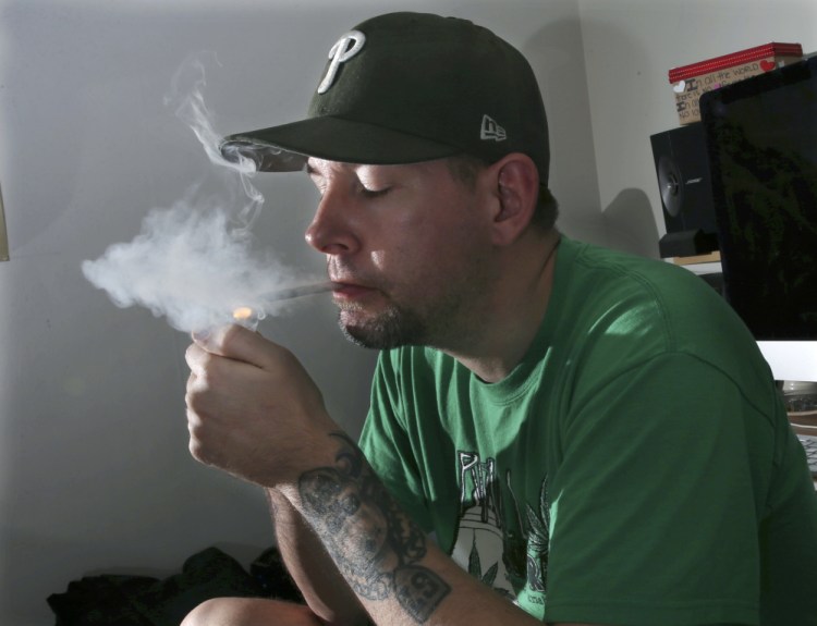 Former U.S. Marine Mike Whiter lights a marijuana cigarette before he starts editing a video project at his home in Philadelphia. A growing number of states are weighing whether to legalize marijuana to treat PTSD. While the research has been contradictory and limited, some former members of the military say marijuana helps them manage their anxiety, insomnia and nightmares.