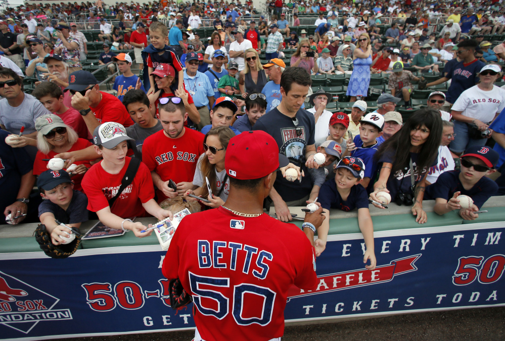Mookie Betts takes a few minutes to sign autographs for fans before Thursday’s spring training game against the New York Mets. The Red Sox won 4-1.