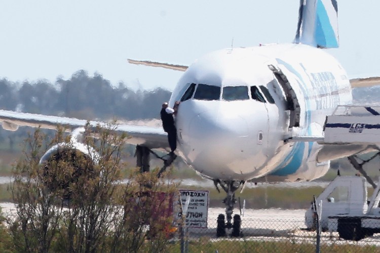 A man  leaves the hijacked aircraft of Egyptair from pilot window at Larnaca airport in Cyprus Tuesday. The Associated Press