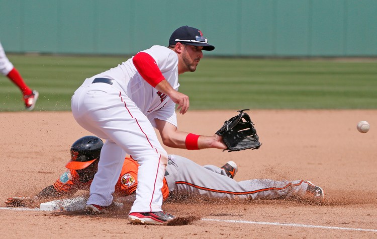 Boston Red Sox third baseman Travis Shaw reaches out for the ball as Baltimore Orioles' Xavier Avery steals third in a spring training gameon Monday in Fort Myers, Fla. The Associated Press