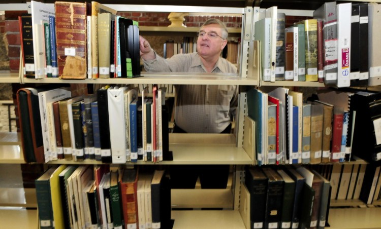 Dale Jandreau, librarian at Skowhegan Free Public Library,, selects a book of documents on area families Wednesday in the library's new genealogy section.
