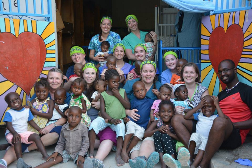 Along with many children from the Real Hope for Heati Center, front, from left, are Susan Baker, faculty member, with Masha LaChance, Jessica Rodrigue and Tiffany Labbe, and Michel Pierre Louis, interpreter. Middle row, from left, also sporting bandannas, are Patrick Caskin, Emily Karter and Jamie Plummer and Allison Woodside; and back, from left, are Mellissa Arroyo and Sarah Coughlin. All but three are wearing UMA bandannas.