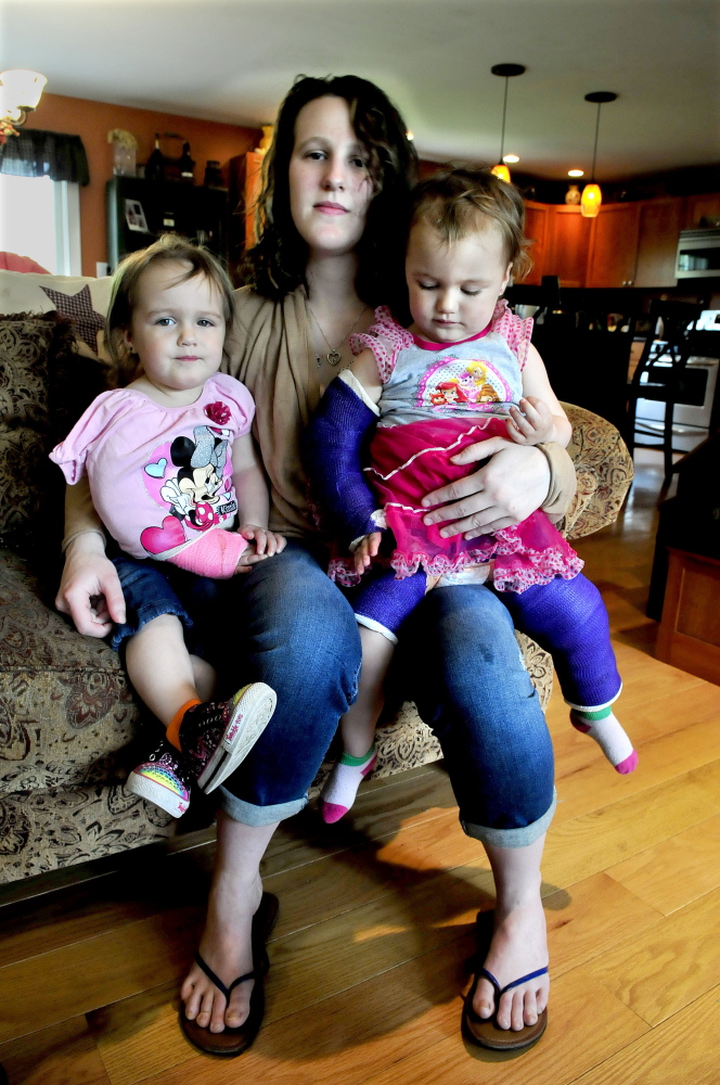 Emily Walker, now Emily Davis, holds her twin 2-year-old daughters Maddilyn, left, and Brooklyn in May 2014 at an undisclosed location after the girls were injured while in the care of David M. Devine.