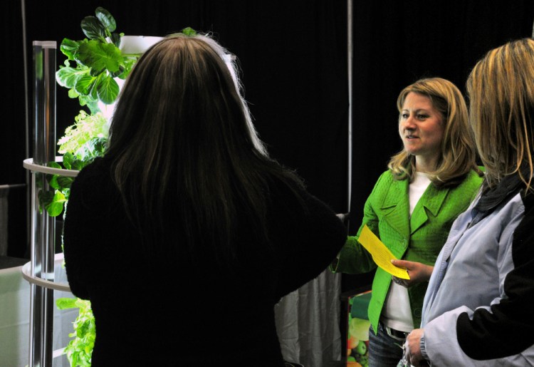 Natalia Irving, center, talks to customers about a tower garden Friday during the 43rd annual Manchester Lions Club Home and Garden Show at the Augusta Civic Center.