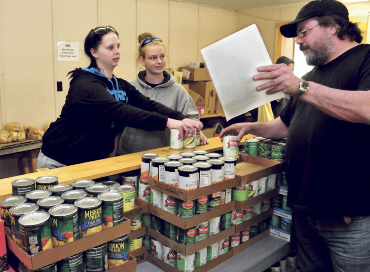 Brittany Ward, left, and Andrea Rowe receive food items Wednesday from volunteer Ty Parson at the Skowhegan Food Cupboard.