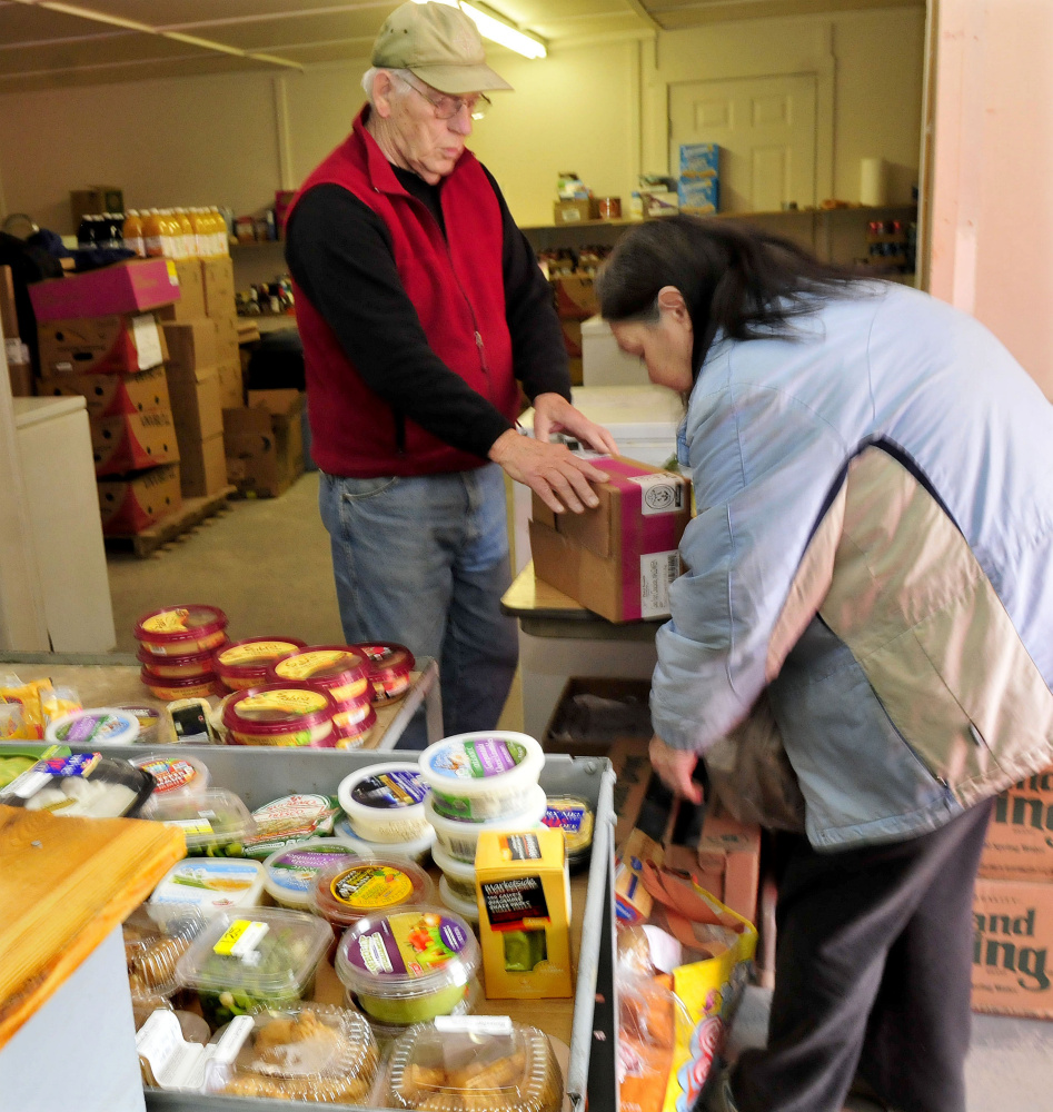Skowhegan Food Cupboard volunteer Richard Boone helps client Kathy Searles with food items on Wednesday.