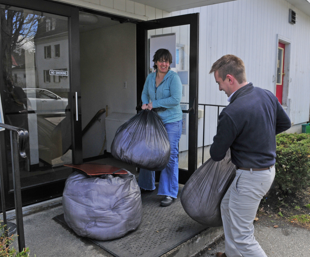 Sarah Miller, the Augusta Food Bank director, left, holds the door for Chris Lothridge, sales manager of the Hampton Inn in Augusta, as he carries in bags of linens for Addie's Attic on Friday at the St. Mark's Episcopal Church parish hall in Augusta. Several local hotels are collecting and donating linens and personal care products to Addie's Attic and the Every Day Basics Essentials Pantry that are operated in the building on Pleasant Street.