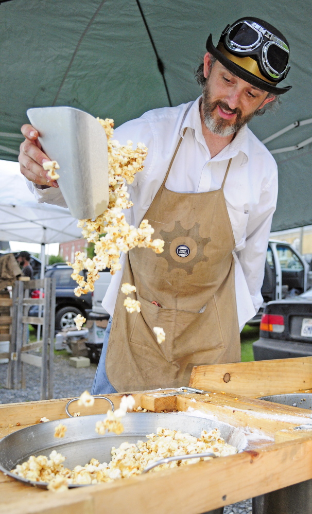 Thomas Villegas tosses freshly popped kettle corn to keep it from sticking together before packing it into bags July 21, 2015, at the Hallowell Farmers Market in downtown Hallowell. Market organizers plan to move the market to a new location this year — the Public Utilities Commission lot between Winthrop and Central streets.
