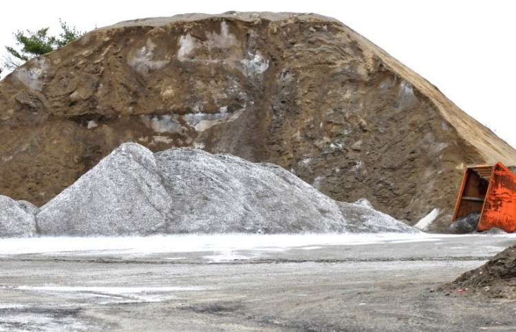 Light colored salt is stored beside a large pile of sand used for winter road work at the Winslow Public Works garage on Monday. Nearby homeowner Cory Dow says that salt from the pile has contaminated his well.