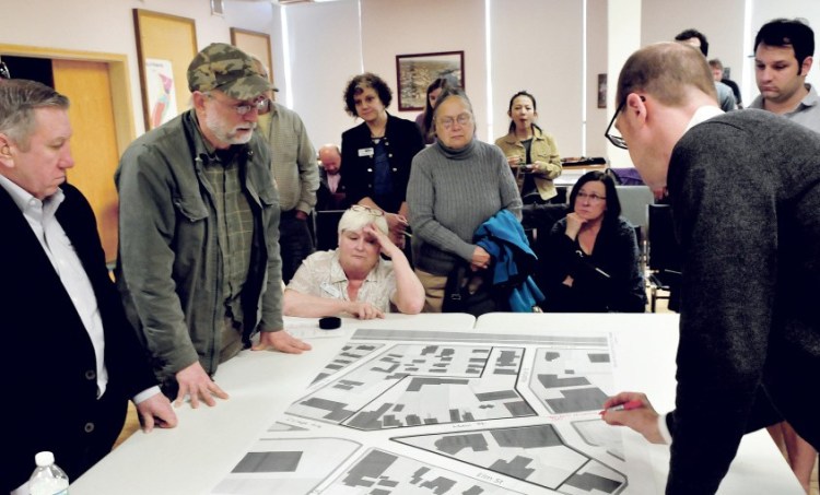 Bruce Fowler, wearing a cap, asks questions of planner Neil Kittredge, right, over a section map of downtown Waterville during a revitalization discussion Wednesday.
