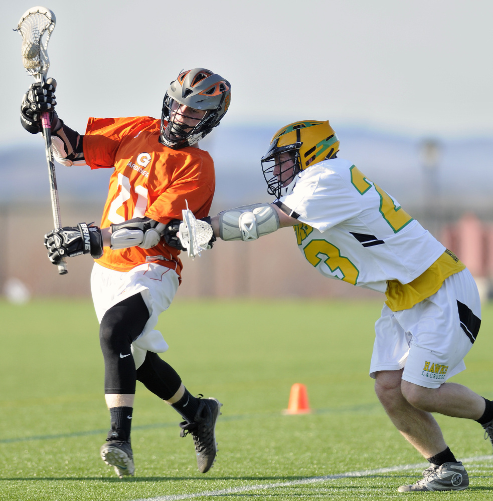 Gardiner Area High School's Sloan Berthiaume, left, gets checked by Maranacook Community High School's Drew Davis during a boys lacrosse game Tuesday in Readfield.