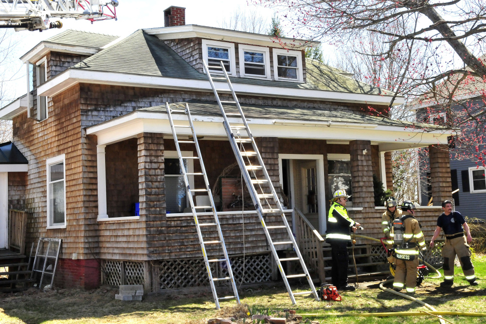 Waterville firefighters, including Chief Dave Lafountain, left, set up a fan Thursday to ventilate smoke from a home on Colonial Street in Waterville. Officials think an electrical problem in the attic caused the fire.