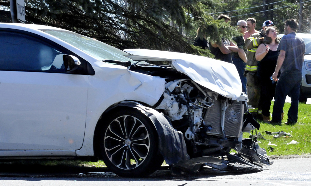 A woman is treated near a demolished vehicle following a two-car accident at the intersection of Davis and Six Rod roads in Fairfield Sunday.