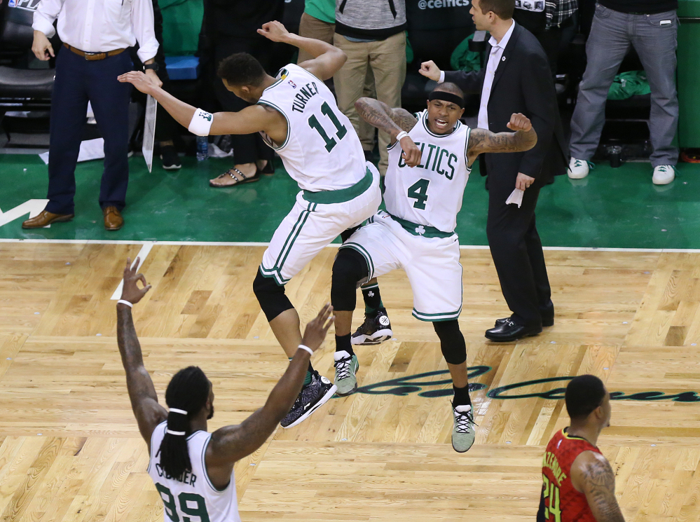 Atlanta's Kent Bazemore, lower right, walks off the court as the Boston's Isaiah Thomas (4) leaps to celebrate hitting his three pointer with teammate Evan Turner, while Jae Crowder, lower left, also celebrates in Game 4 of a first-round NBA playoff series Sunday in Boston .