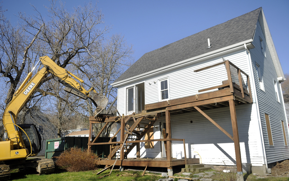 Adam Mealey rips off the deck of the house at 226 Water St. in Hallowell during demolition on Monday.
