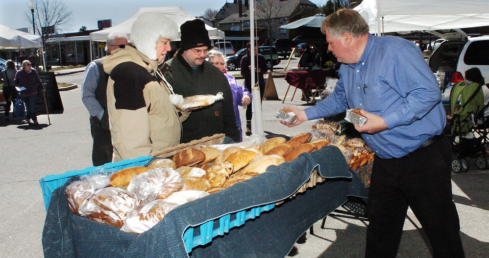 Karl Rau, of Good Bread, sets out his products as customers Jeannie and David Gubbins Jr. wait to buy bread Thursday at the Downtown Waterville Farmer's Market. The market opened for the season and will be in The Concourse parking lot every Thursday through Nov. 17.
